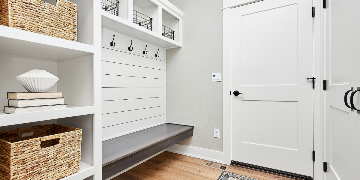 A chic entry room with shelves, hooks to hang jackets, a bench for seating, and decorative storage bins. 