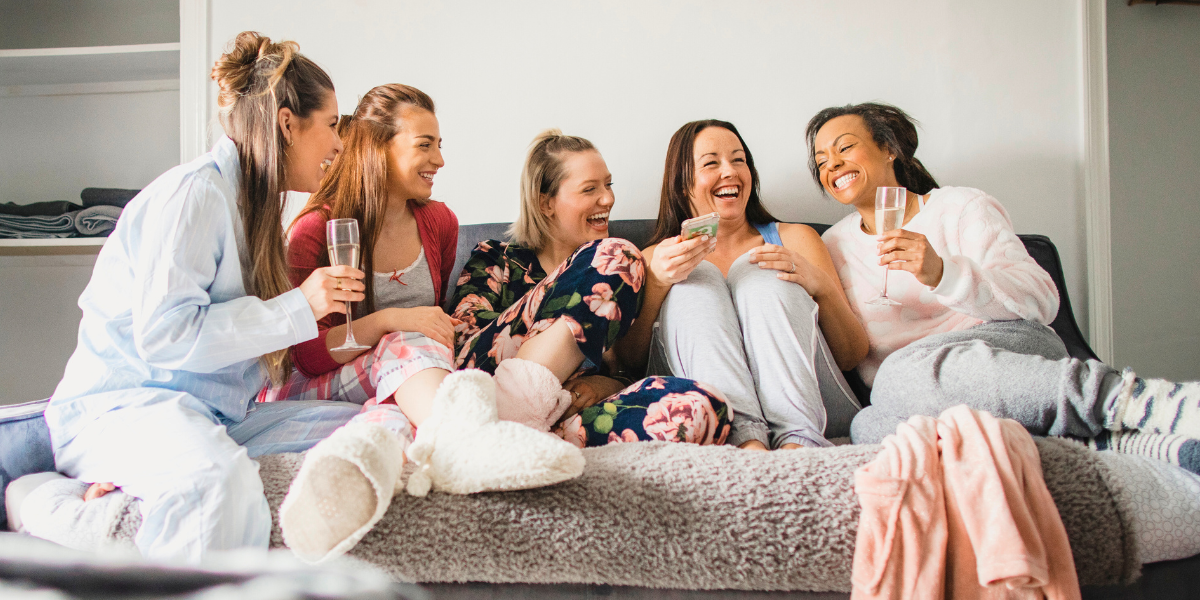 Women on a couch laughing and drinking together.