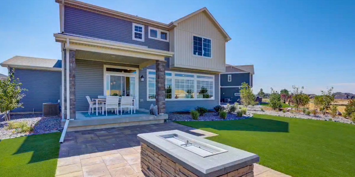 Backyard of two-story house with a large lawn.