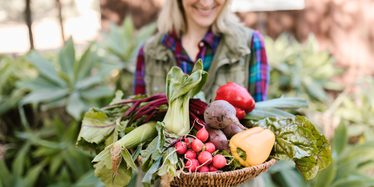 Person holding cornucopia full of fresh produce.