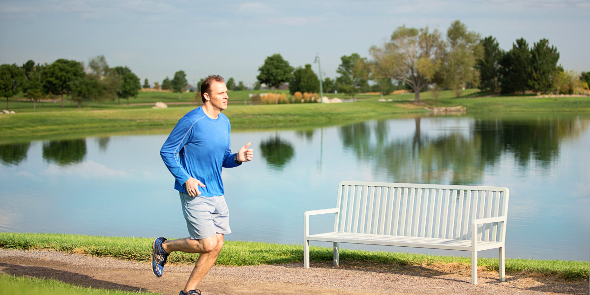 Man jogging along a trail next to a large lake. 