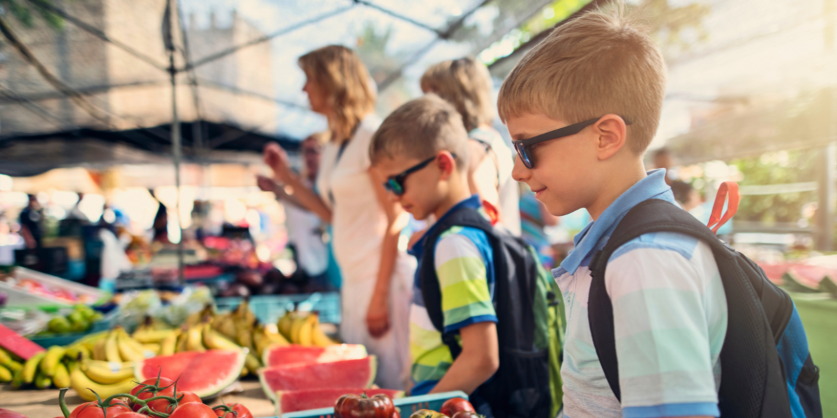 Children looking at a stand of fruit at the local farmers' market