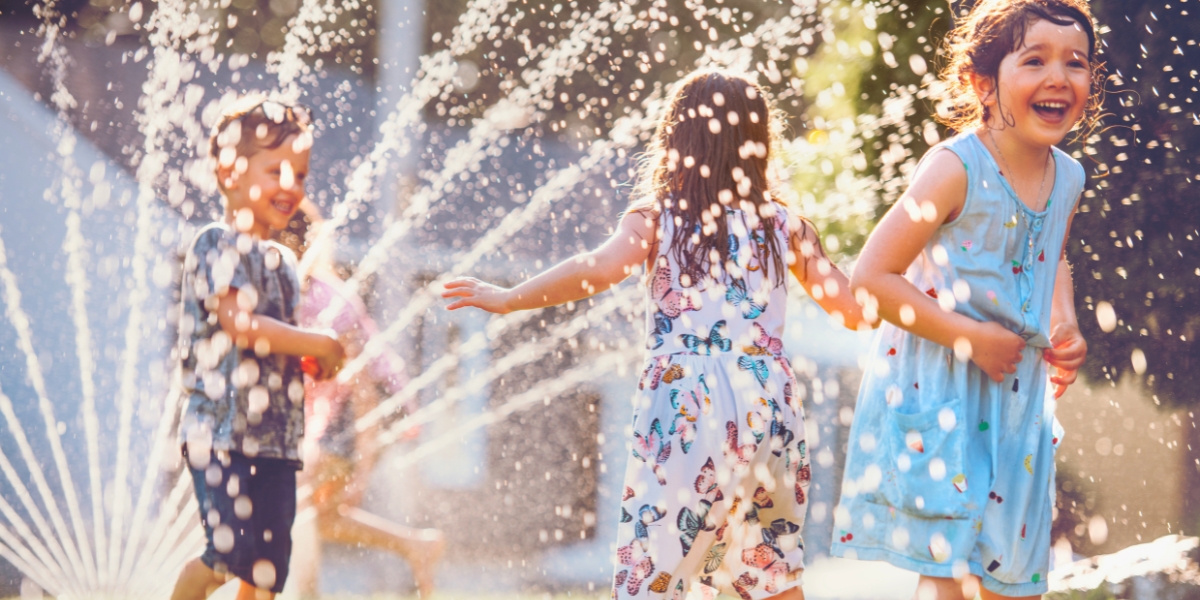 Children playing in sprinklers in backyard.