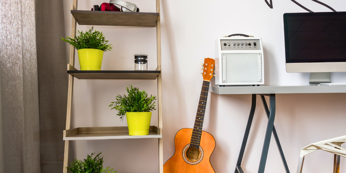Guitar next to an amp near a bookshelf in a music-themed room. 