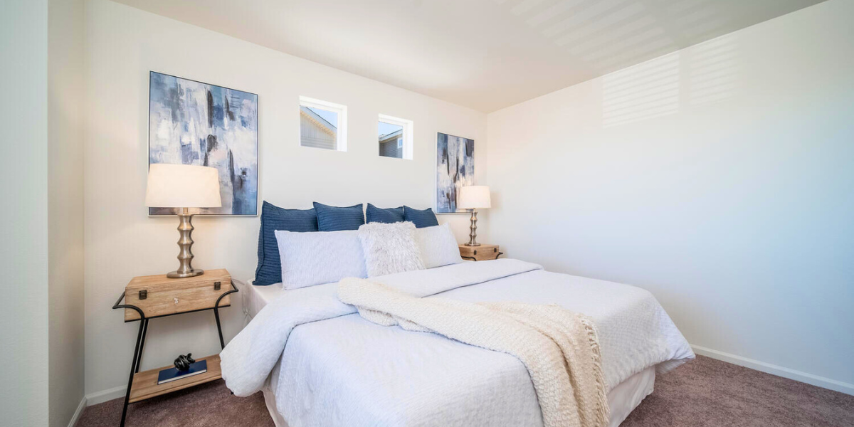 Beautiful bright bedroom with a throw cover, and lots of pillows on a neatly made bed.