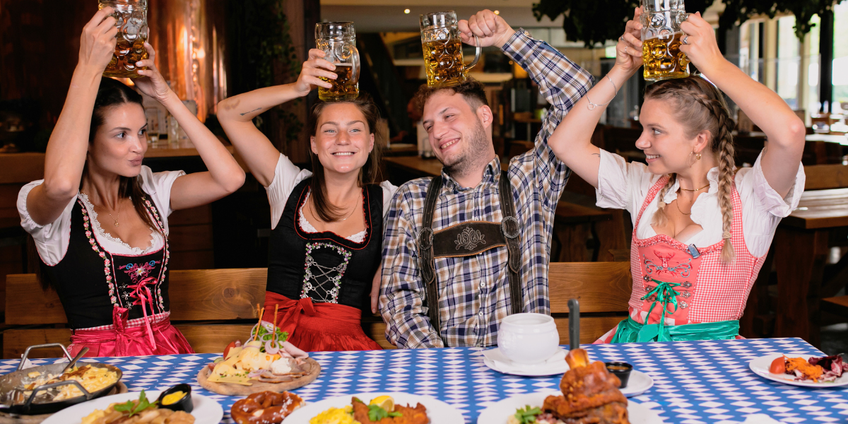 People dressed in lederhosen and dirndls enjoying a beer at Oktoberfest.