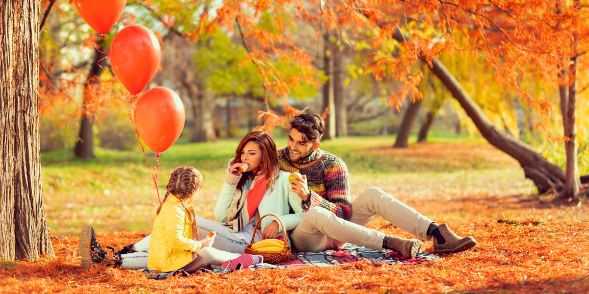 Family picnic outside surrounded by fall foliage. 